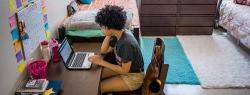 非裔美国女性在宿舍的桌子上用笔记本电脑工作