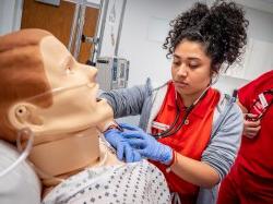 女护理系学生在模拟实验室与医疗人体模型.